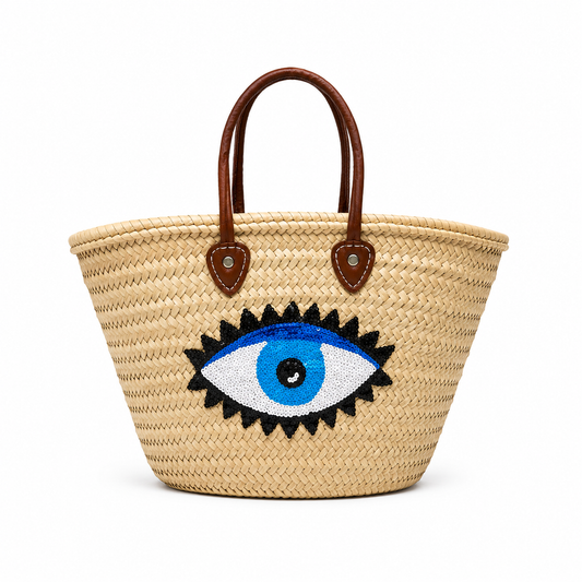 Handwoven Moroccan straw beach bag featuring a blue evil eye design with genuine leather handles.